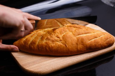 Ev yapımı beyaz ekmek büyük bir bıçakla kesilir. Evde pişirme.