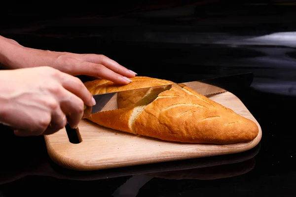 Domowej roboty biały chleb jest krojony dużym nożem. Pieczenie w domu. — Zdjęcie stockowe