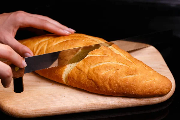 Homemade white bread is cut with a large knife. Baking at home. — Stock Photo, Image