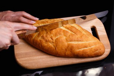 Ev yapımı beyaz ekmek büyük bir bıçakla kesilir. Evde pişirme.