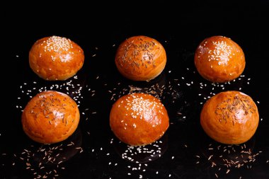 Susamlı beyaz çıtır çörekler. Siyah arkaplanda fotoğraf.