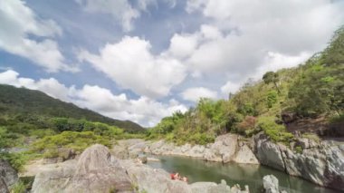 Bir grup genç bir derede eğleniyor. New Caledonia dağlarında öğleden sonra. Bulutların ve mavi gökyüzünün varlığı.