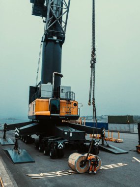 Kıyıdan kargo gemisine çelik bobinler yükleniyor. Kıyı vinç ile yükleme için bobinleri slig işçi. 