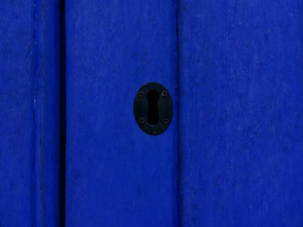 Black keyhole on bright blue wooden panelled door with copyspace — Stock Photo, Image