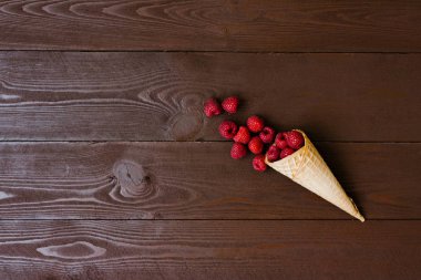 Taze organik ev yapımı bahçe ahududu bir waffle koni, kahverengi bir arka plan üzerinde dondurma konisi. Alan sol görünümü kopyalama