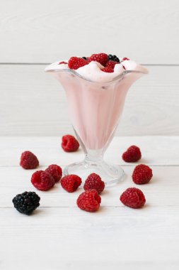 Güzel pembe ahududu snack meyve smoothie veya milkshake beyaz bir kalas üzerinde ahududu ve böğürtlen ile bir bardak . Yoğurt kokteyli. Doğal detoksifikasyon. Sıvı dondurma.