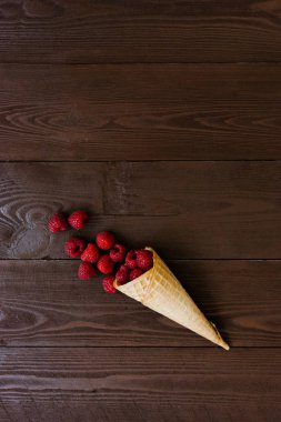 Kahverengi ahşap arka plan üzerinde bir waffle koni taze ahududu. tatlı meyve bir menü kavramı. ahududu dondurması. organik gıda. Kopyalama alanı