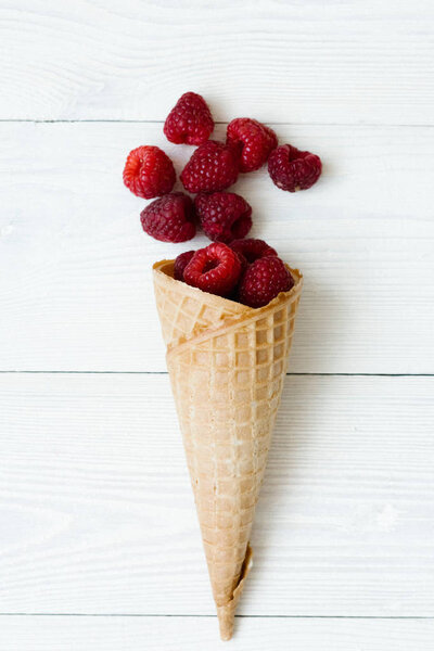 Fresh raspberries in a waffle cone on white wooden background. the concept of a menu of sweet fruit. raspberry ice cream. organic food. 