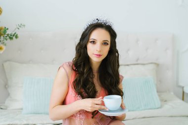 pembe dantel negligee çay mavi bir Fincan tutan zarif gelin. düğün töreni ve düğün öncesi rahatlama. profesyonel makyaj ile güzel bir kız sabah çay partisi
