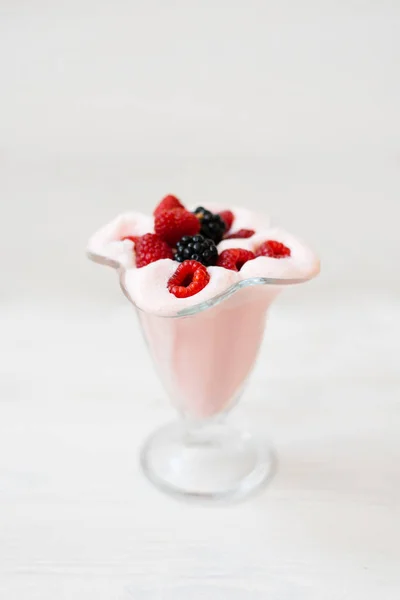 A glass of refreshing raspberry milkshake for breakfast, lunch or dinner with fresh raspberries and blackberries on a white background. Menu for a cafe or restaurant