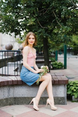 Bir buket gül, şehir eğlenceve yürüyüş ile Park'ta bir yaz sokakta yürüyen genç bir kız romantik görüntü. Elinde bir buket gülle bir bankta oturmak.