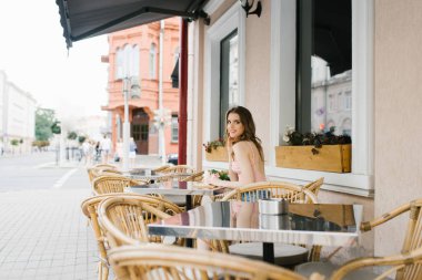 Sevimli kahverengi saçlı genç kız bir kafede açık havada oturan, rattan sandalye yalnız. Etrafta kimse yok. Birini bekliyor ve istiyor.