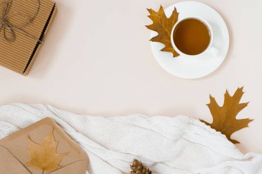 bir fincan çay ile güzel sonbahar kompozisyon. sonbahar yaprakları, Kraft hediye kutusu, bir zarf ve bej arka plan üzerinde bir örgü battaniye. sonbahar sezonu kavramı. kopyalama alanı