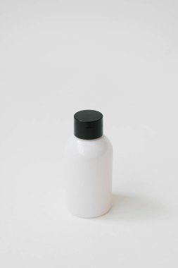 Beyaz bir arka plan üzerinde bir kağıt beyaz paket içinde duş veya banyo, beyaz ve pembe şişeler için kozmetik ürünleri seti. kopyalama alanı