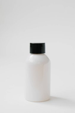 Beyaz arka planda vücut bakımı kozmetik veya saç için siyah kapaklı plastik şişe. Yan görünüm