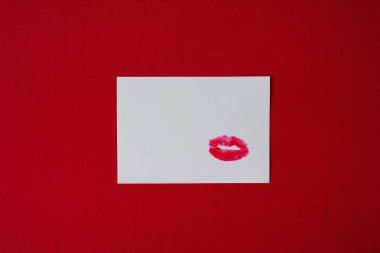 Öpücük izi kırmızı arka plan ile beyaz kağıt üzerinde kırmızı ruj ile yapılır. Kopya alanı. Sevgililer günü kartı