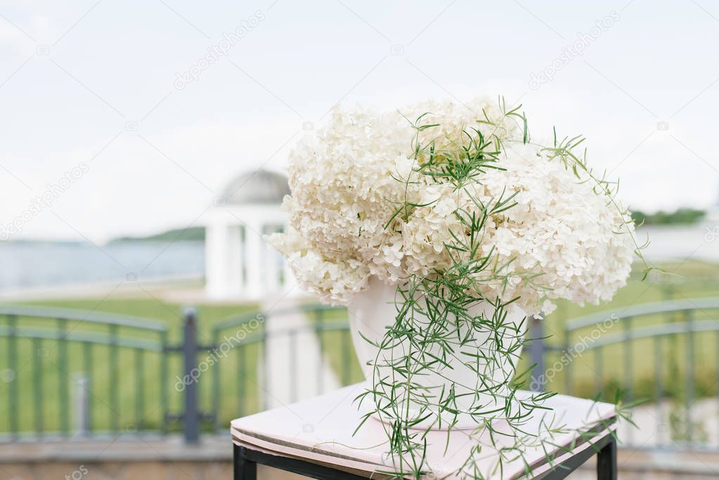The composition of white hydrangea in a white flowerpot in the decor of the wedding registration of marriage . Close up