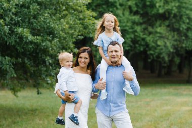 Güzel bir ailenin portresi: anne, baba, iki yaşında bir oğul ve beş yaşında bir kız. Ebeveynler çocukları kollarına alır. Aile mavi ve beyaz giyinmiş.