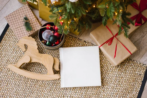 Beyaz deri kapaklı fotoğraf kitabı, düğün veya Noel ağacının altında Noel hediyeleriyle çevrili aile fotoğrafı albümü.