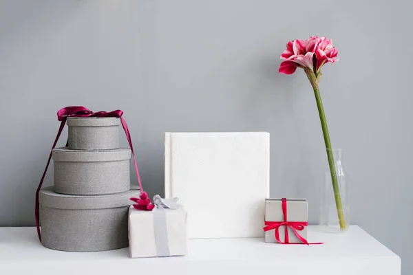 Fotobok Omgiven Presentförpackningar Gåva Och Blomma Vas Grå Vägg Bakgrund — Stockfoto