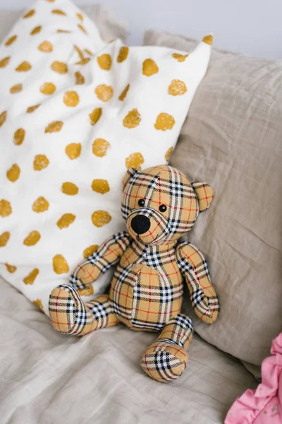 Toy handmade plaid bear on the bed in the pillows