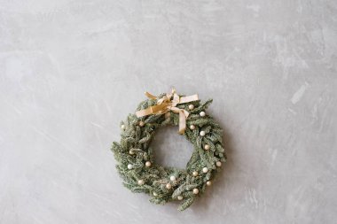 Gri duvarında bej fiyonklu güzel, narin Noel çelengi, kopyalama alanı