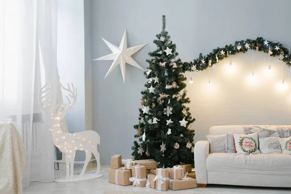 Oturma odasının iç tarafında güzel bir Noel ağacı duruyor. Kanepesi ve ışıklı bir geyiği var.