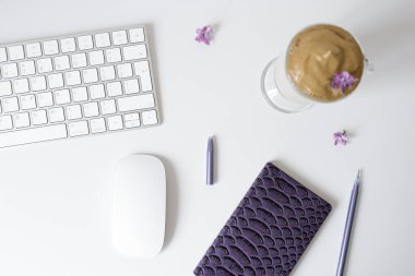 Açık bir kupada Dalgona kahvesi, Not Defteri, masada kalem ve bilgisayar. Üst Manzara. İş yerinde kahve molası..