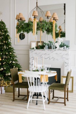 Şenlikli Noel masası mermer şöminenin yanında klasik sandalyeler ve oturma odasında Noel ağacı ya da evdeki yemek odası.