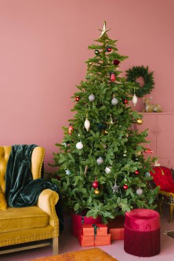 Pembe oturma odası tarzında Noel ağacı. Turkuaz ekose ve kestane rengi kadife banketli klasik sarı kanepe. Noel arkaplanı.