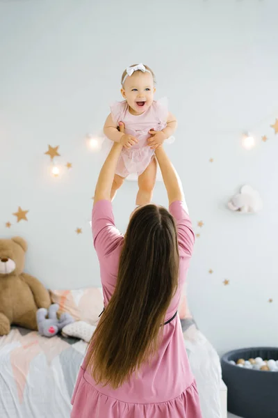 The concept of motherhood, infancy and people-the mother throws the child up, laughing and playing with it in the nursery