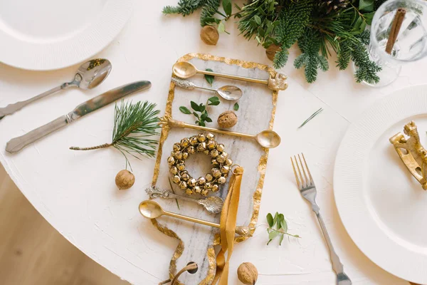 Glass cutting Board with a Christmas wreath on it, walnuts and Cutlery in the Christmas table setting