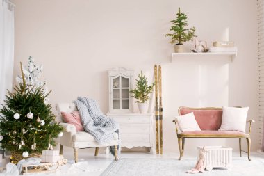 Oturma odasında Noel ağacı ve yastıklı kanepesi olan rahat bir Noel dekoru. Kayaklar duvara dayanıyor. Yılbaşı için çocuk odasının klasik tasarımı.