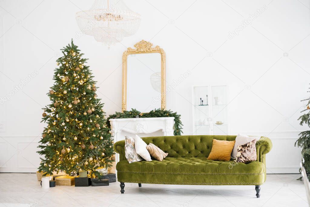 Stylish design of the living room with Christmas decor in vintage style with a green sofa, fireplace, Christmas tree decorated with toys and lights