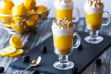 Parlak ışıklı bulanık arka plan karşı yemeye hazır limon beze pasta tatlı bardak ekran yakından.