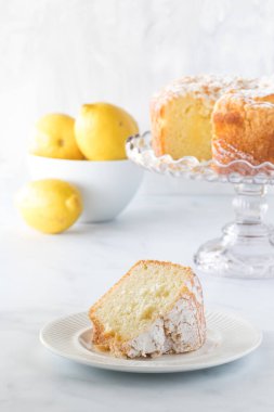 Bir dilim limonlu kek, kek tezgahında pasta ve bir kase parlak limon..
