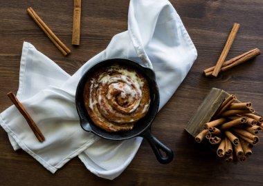 Tarçın çubuklarıyla çevrili kızartma tavasında tarçınlı çörek..