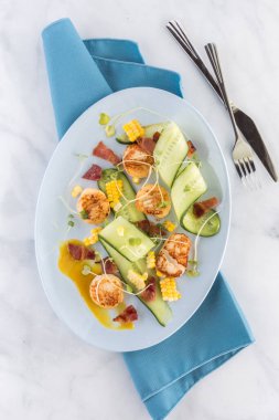 Lezzetli karides ve domuz pastırması aperatif salatası oval tabakta servis ediliyor. Üst alt görünüm.