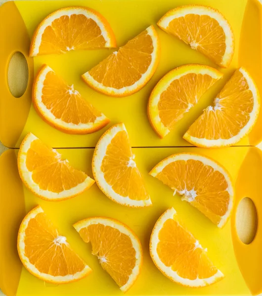 Slices of navel oranges on bright yellow cutting boards. Abstract background. — Stock Photo, Image