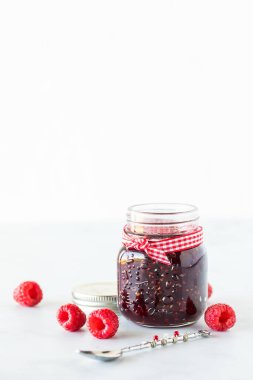 Üstünde fotokopi alanı olan küçük bir kavanoz ahududu reçeli. Dikey biçim