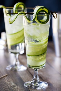 Salatalıklı kokteyl spritzer ve siyah bir arka planda salatalık..