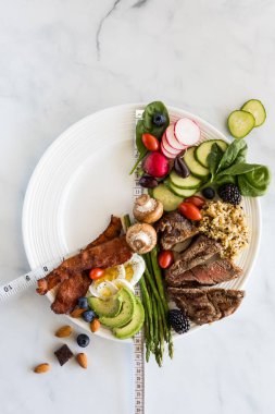 16: 8 Perhiz Konsepti. Beyaz bir tabakta beyaz mermer arka planda çeşitli düşük karbonhidratlı yiyecekler..