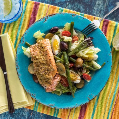 Turkuaz tabakta somon filetosu ile Nicoise salatası yenmeye hazır..