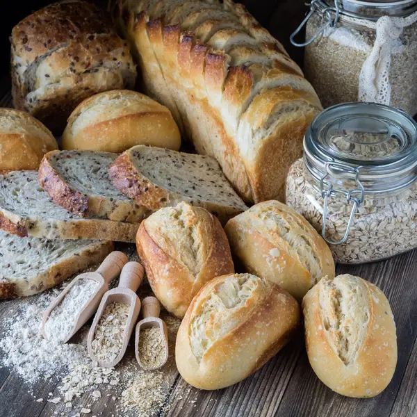 El primer plano del arreglo de los panes distintos de masa fermentada y los bollos con los ingredientes de la harina y la avena. — Foto de Stock