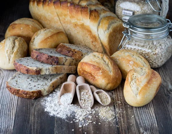 Surtido de panes con ingredientes en frente en una mesa de madera. — Foto de Stock
