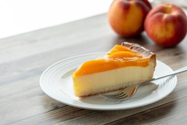 Güneşli bir pencereye karşı bir dilim lezzetli şeftalili peynirli kek.. 