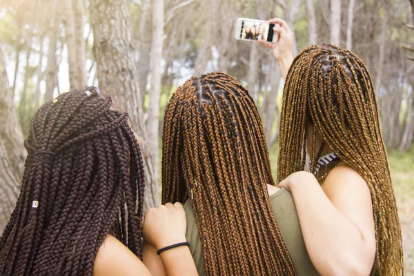 Три молодые и красивые девушки, с плетеными волосами, делают селфи — стоковое фото