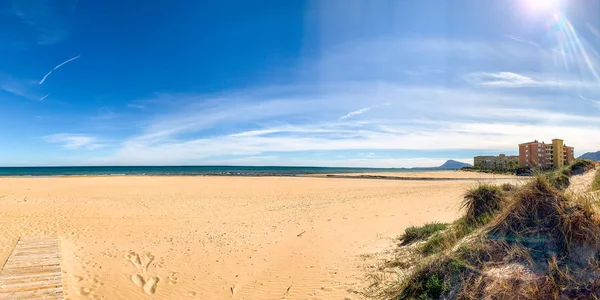 Una playa desierta y un río en Denia, España con un poco de vegetación en primer plano y montaña Montg de fondo — Foto de Stock