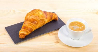 Ahşap bir yüzeyde kruvasan ve kahve