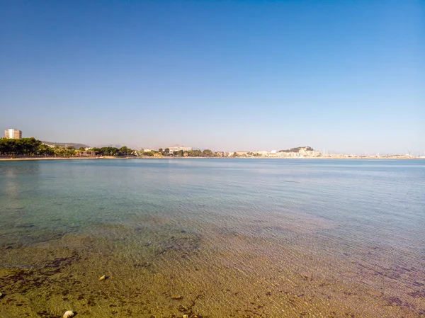 Flying backwards over Marineta Beach in Denia, Spain. The city and the ancient Denia castle are in the backgroundMarineta Beach in Denia, Spain. The city and the ancient Denia castle are in the backgr — Stock Photo, Image